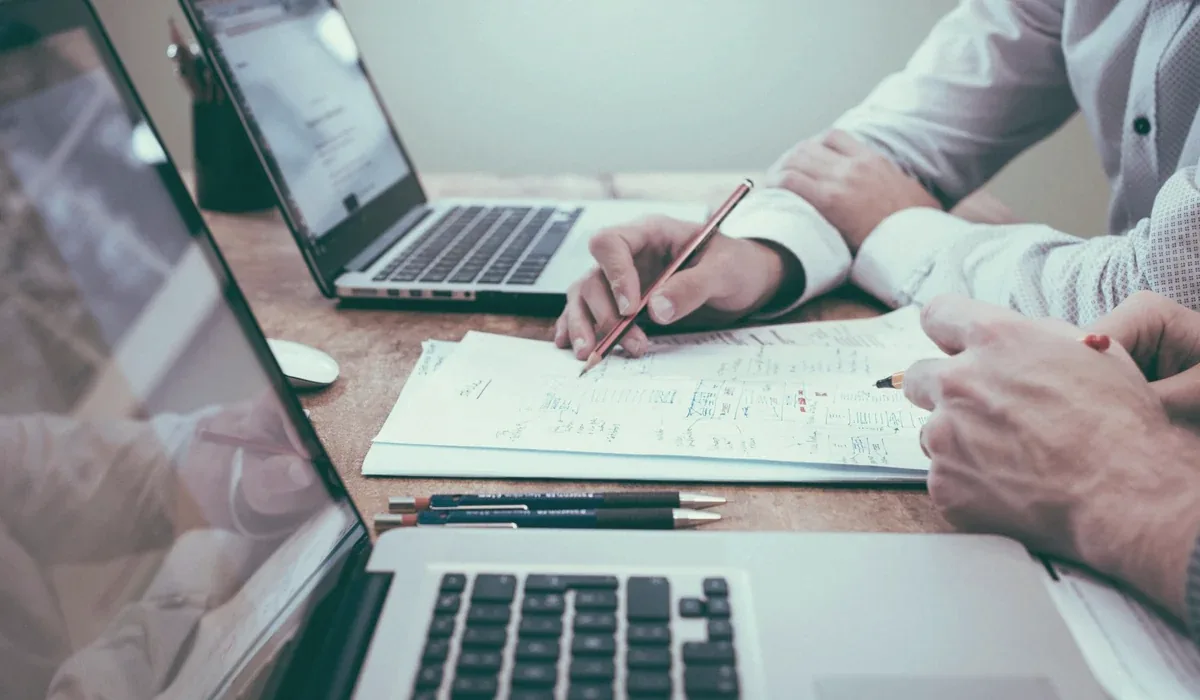 Pessoas analisando documentos em uma mesa de trabalho